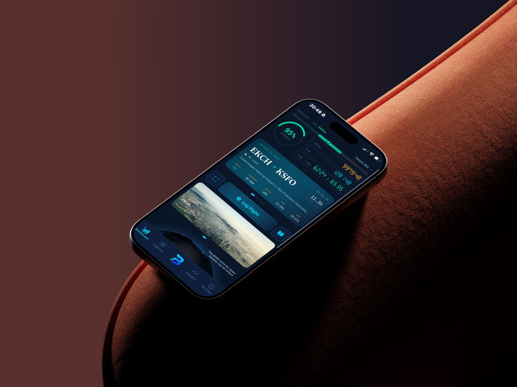 An iPhone resting on a velvet armchair, showing the BLADES dashboard with the latest flight, EKCH to KSFO, 11.3 hours.